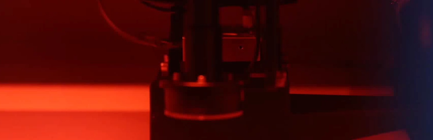 Laser drilling machine machining microvias on a PCB panel under red alignment light