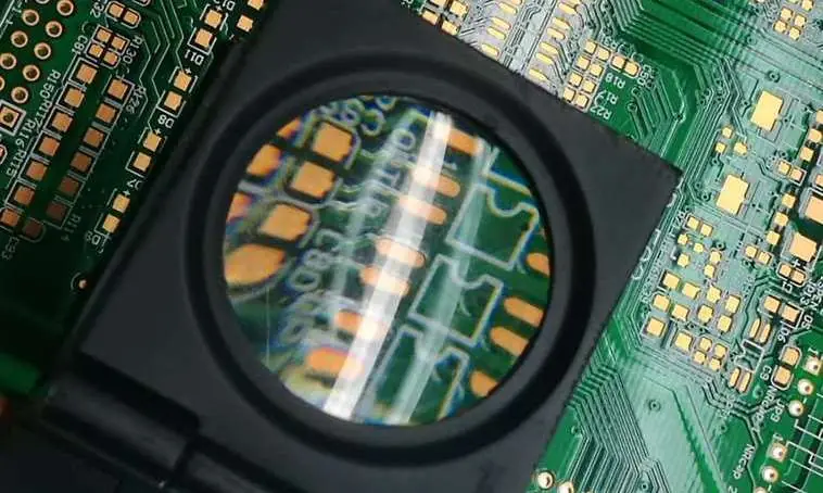 Engineer inspecting a finished PCB under magnification before reliability checks